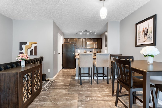 9137 Parkpoint Ln, Lewis Center, OH 43035 - dining space with light wood-style floors, a textured ceiling, baseboards, and track lighting