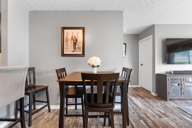 9137 Parkpoint Ln, Lewis Center, OH 43035 - dining space featuring wood finished floors, a textured ceiling, and baseboards
