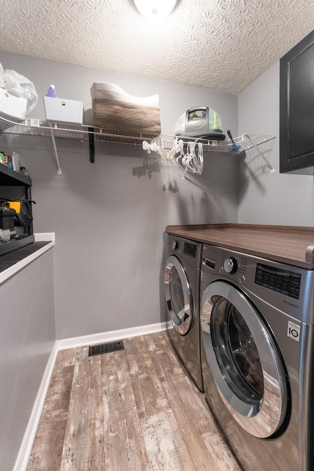 9137 Parkpoint Ln, Lewis Center, OH 43035 - laundry area with washer and dryer, light wood-type flooring, a textured ceiling, and baseboards