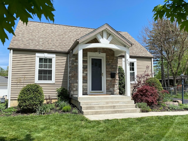 view of front of house with a shingled roof and stone siding