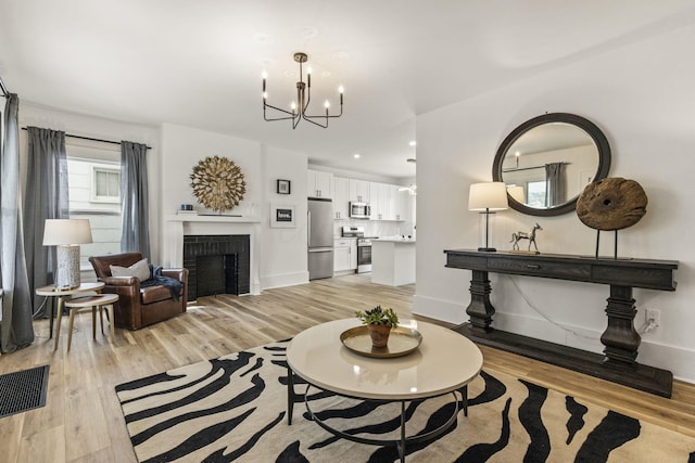 147 N Ogden Ave, Columbus, OH 43204 - living area featuring visible vents, light wood finished floors, a notable chandelier, and a fireplace