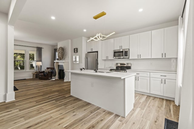 147 N Ogden Ave, Columbus, OH 43204 - kitchen with appliances with stainless steel finishes, a sink, light wood finished floors, white cabinetry, and open floor plan
