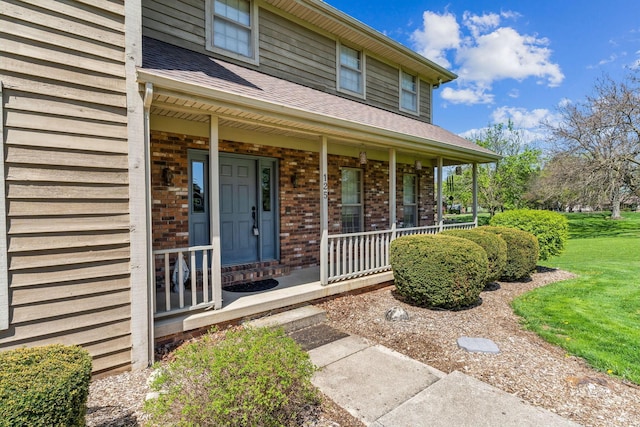 125 W Woodmere Dr, Tiffin, OH 44883 - doorway to property with brick siding, a shingled roof, a lawn, and covered porch