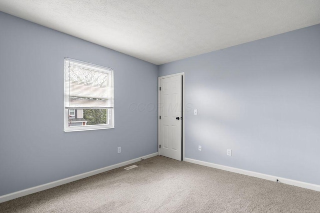 unfurnished room with baseboards, carpet flooring, a textured ceiling, and visible vents