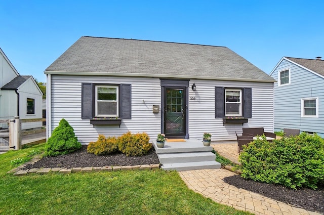 cape cod-style house featuring roof with shingles and fence