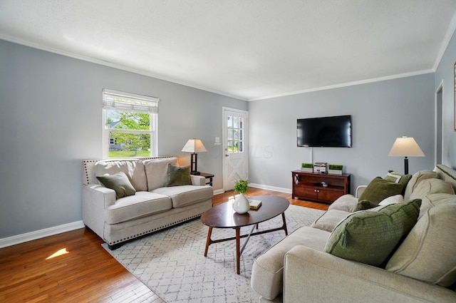 living area with ornamental molding, wood-type flooring, and baseboards