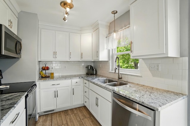 kitchen featuring a sink, stainless steel appliances, decorative backsplash, white cabinets, and light stone countertops