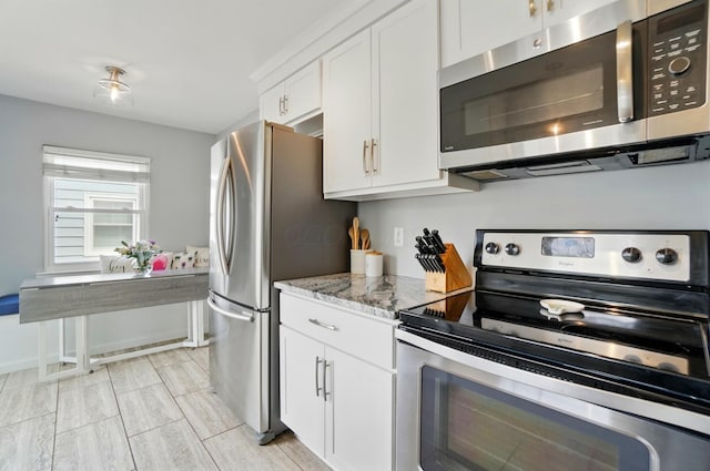 kitchen featuring light stone countertops, stainless steel appliances, and white cabinets