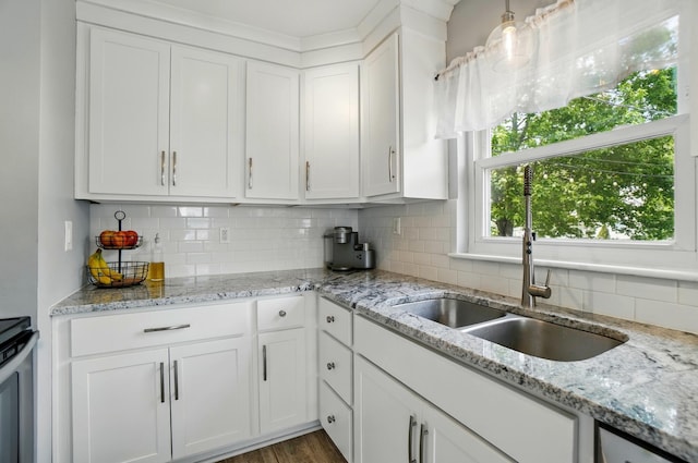 kitchen featuring white cabinetry, stove, light stone countertops, and backsplash