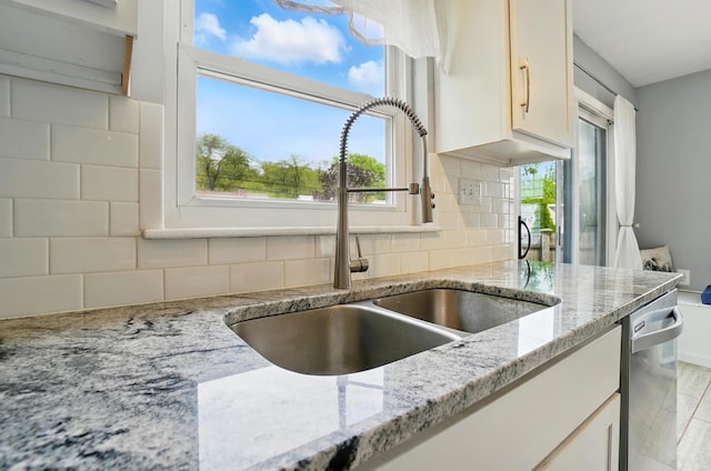 kitchen featuring a sink, stainless steel dishwasher, tasteful backsplash, and plenty of natural light