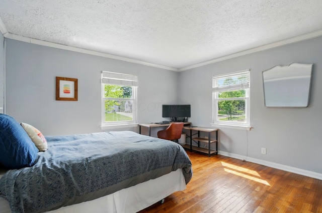 bedroom with baseboards, crown molding, a textured ceiling, and hardwood / wood-style flooring