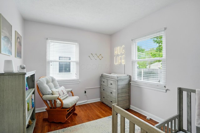 bedroom with a crib, wood finished floors, and baseboards