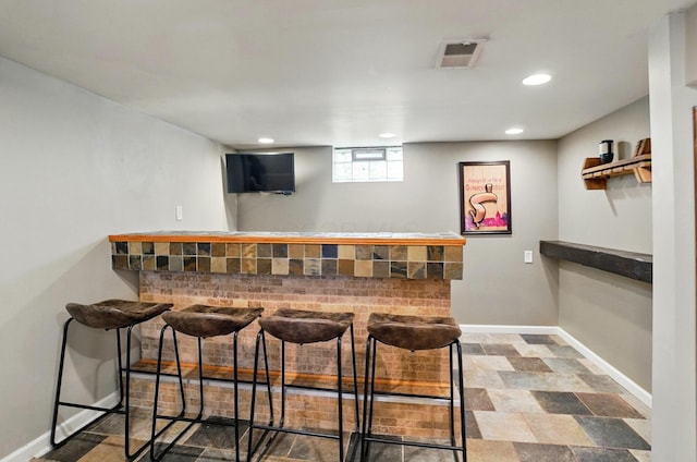 bar with baseboards, visible vents, a bar, and recessed lighting