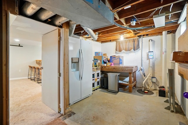 unfinished basement featuring white refrigerator with ice dispenser