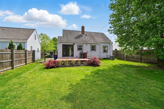 back of property featuring a fenced backyard, central AC unit, a chimney, and a lawn