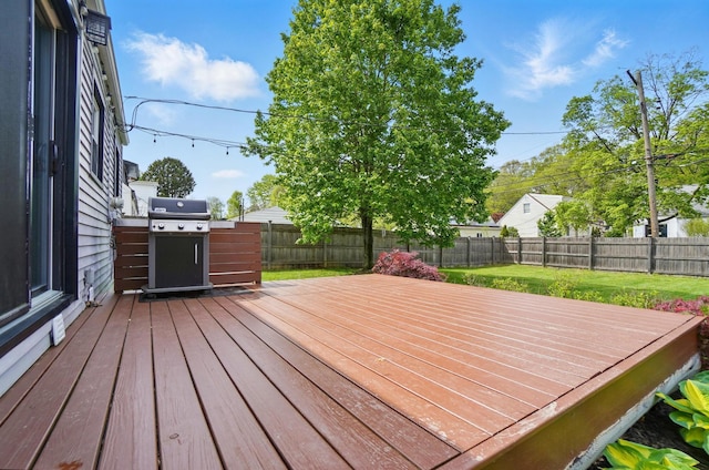 deck featuring a fenced backyard, a grill, and a lawn