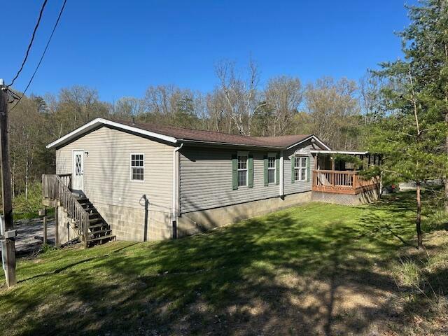 back of property with a wooden deck, a yard, and stairway