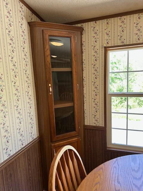 35310 Geiger Rd, Logan, OH 43138 - dining area with a wainscoted wall, a textured ceiling, wooden walls, ornamental molding, and wallpapered walls