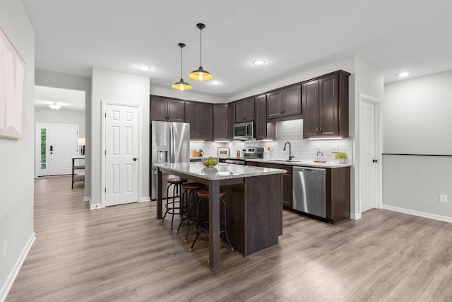 6464 Rockhold Dr, Westerville, OH 43081 - kitchen with appliances with stainless steel finishes, dark brown cabinetry, a kitchen breakfast bar, light wood-style flooring, and baseboards