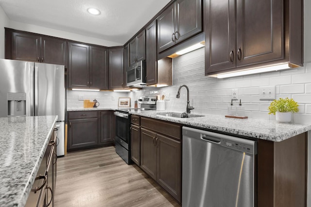6464 Rockhold Dr, Westerville, OH 43081 - kitchen with stainless steel appliances, a sink, light stone countertops, dark brown cabinetry, and a textured ceiling