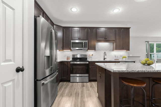 6464 Rockhold Dr, Westerville, OH 43081 - kitchen with stainless steel appliances, light wood finished floors, a sink, dark brown cabinetry, and a kitchen breakfast bar