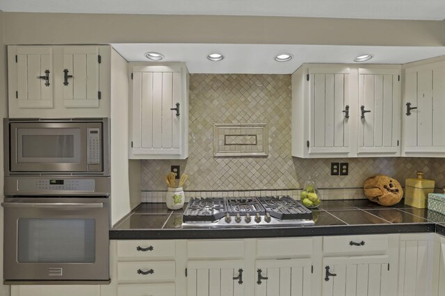 kitchen featuring recessed lighting, decorative backsplash, white cabinetry, and appliances with stainless steel finishes