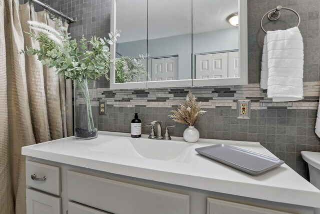 bathroom featuring vanity, backsplash, and toilet