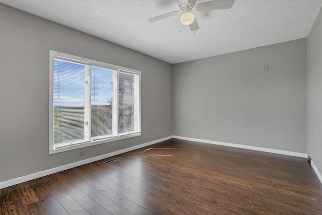 empty room featuring visible vents, dark wood-style flooring, baseboards, ceiling fan, and a textured ceiling