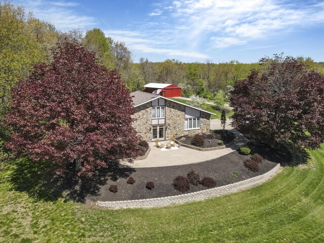 exterior space featuring a view of trees, a patio area, and stone siding