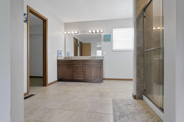 6495 Saylor St, Canal Winchester, OH 43110 - bathroom featuring double vanity, a stall shower, a textured ceiling, a spacious closet, and baseboards