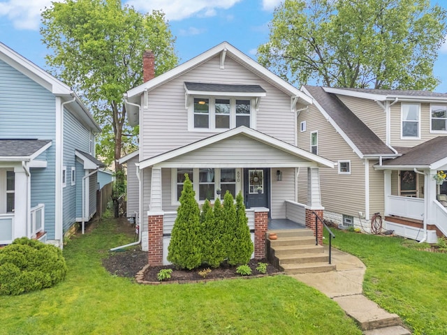 view of front of property featuring covered porch, a front lawn, and a chimney