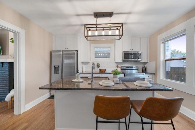 kitchen featuring appliances with stainless steel finishes, a sink, baseboards, and a kitchen bar