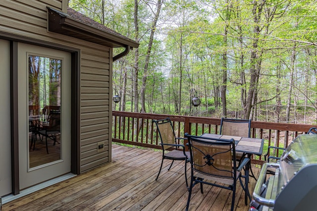 wooden deck featuring outdoor dining area and a wooded view