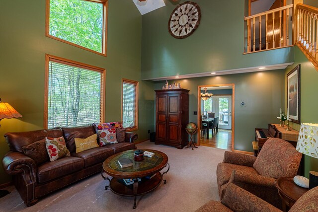carpeted living area with a high ceiling and a notable chandelier