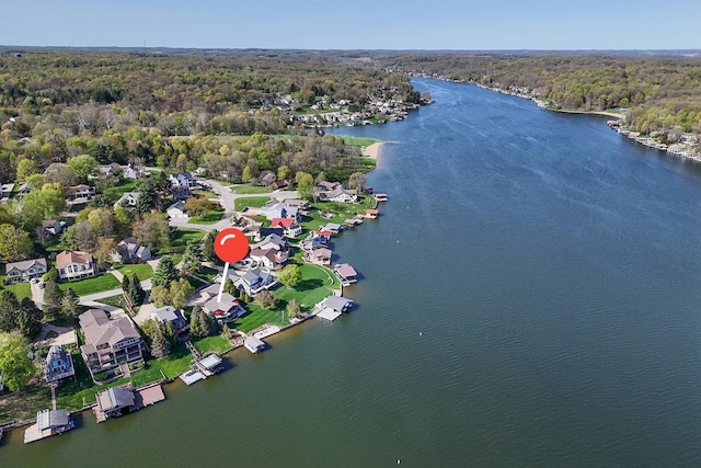 birds eye view of property featuring a water view and a wooded view