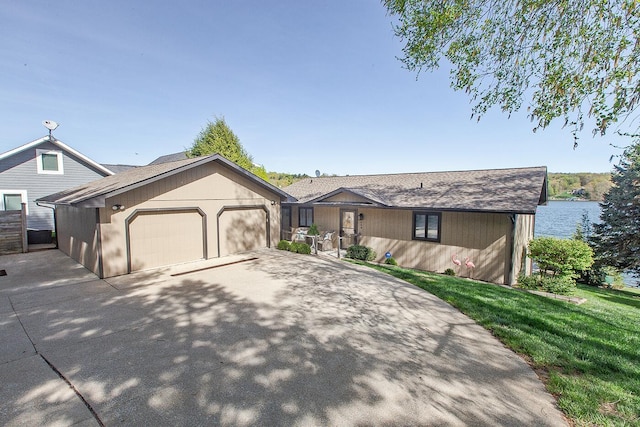 ranch-style home with an attached garage, a shingled roof, driveway, and a front yard