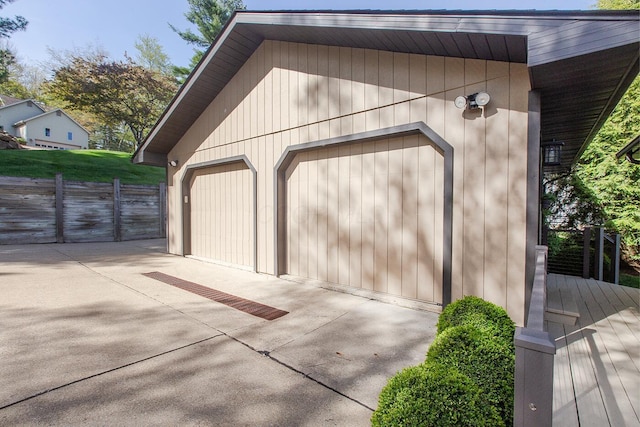 garage featuring concrete driveway and fence