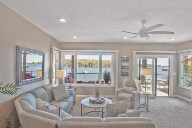 living area featuring a textured ceiling, carpet flooring, baseboards, and plenty of natural light