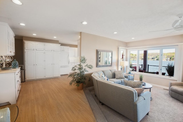 living area with light wood finished floors, a water view, ceiling fan, and recessed lighting