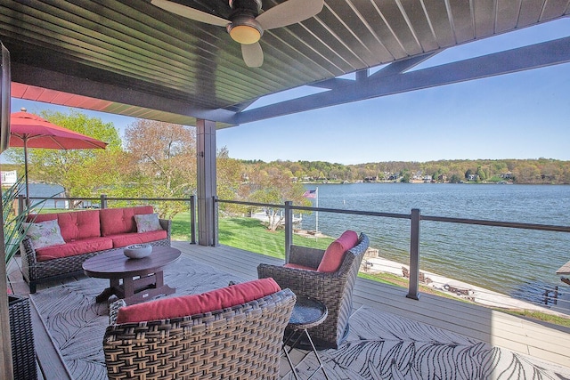 wooden deck featuring a water view, an outdoor hangout area, and a ceiling fan