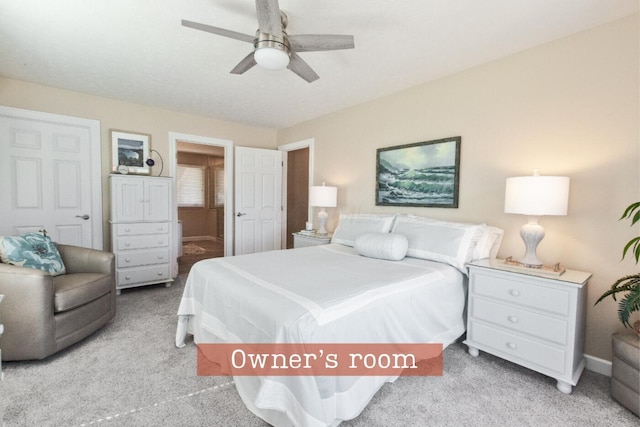 carpeted bedroom with ensuite bath, baseboards, and ceiling fan