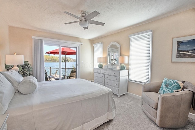 bedroom featuring a ceiling fan, a textured ceiling, baseboards, light colored carpet, and access to outside