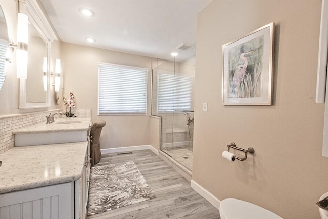 full bathroom featuring toilet, wood finished floors, a stall shower, baseboards, and vanity