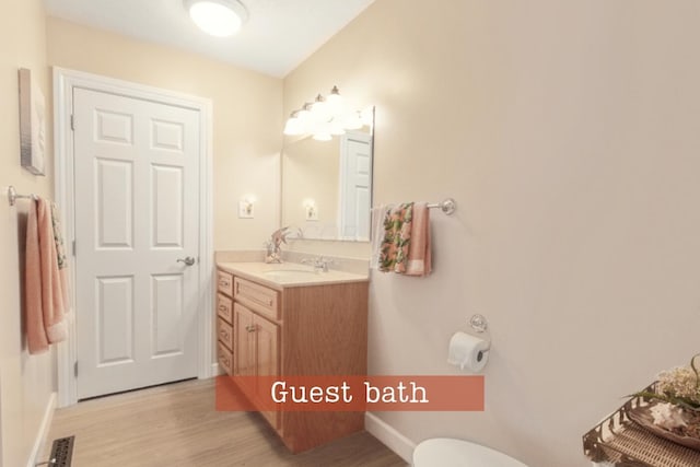 bathroom with vanity, toilet, baseboards, and wood finished floors