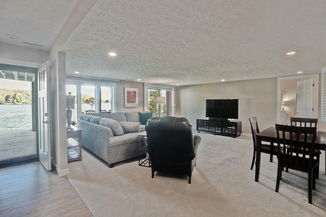 living area featuring a textured ceiling, baseboards, and recessed lighting