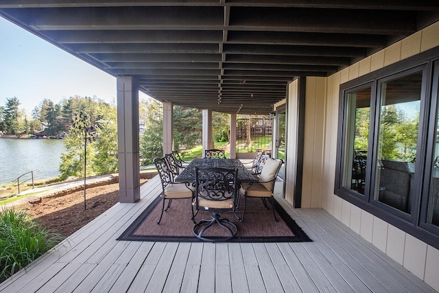 wooden terrace with a water view and outdoor dining area