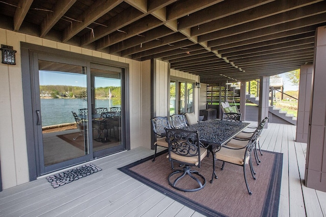 deck with stairway, a water view, and outdoor dining space
