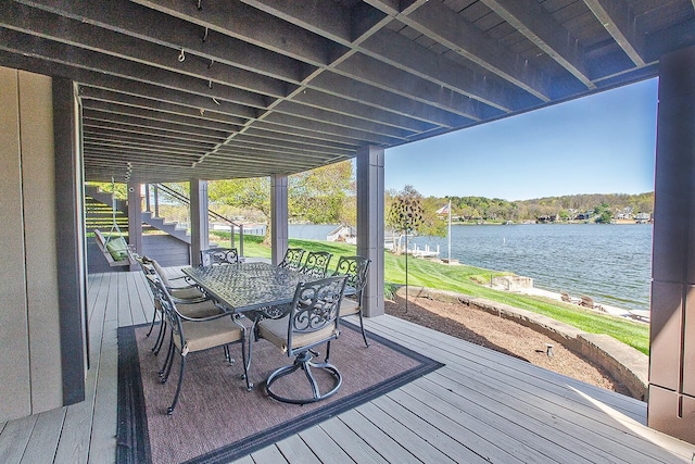 wooden terrace featuring a water view, stairway, and outdoor dining area