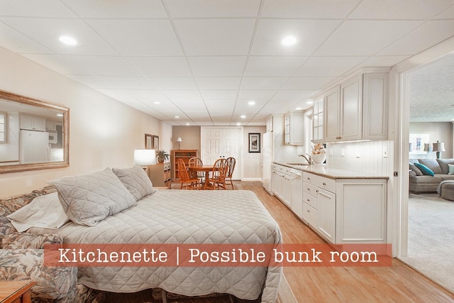 bedroom with freestanding refrigerator, recessed lighting, light wood-style flooring, and a sink