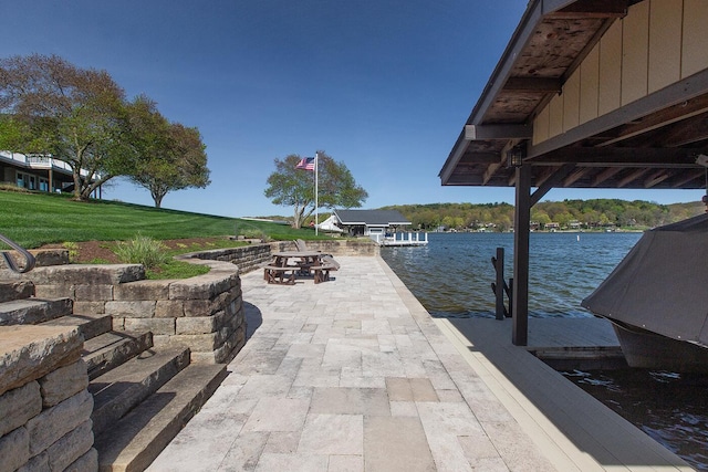 view of patio / terrace featuring an outdoor fire pit, a water view, and a dock
